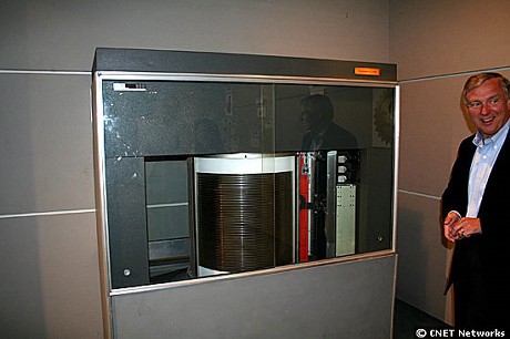 　Hitachi Global Storage Technologies（HGST）のエグゼクティブバイスプレジデントBill Healy氏の右手にあるのは、1インチ（約2.5cm）サイズのマイクロドライブに使用されるプラッタ。左手に持っているのは50年前に登場したIBMの磁気ディスク記憶装置「RAMAC」（Random Access Method of Accounting and Control）に使用された24インチ（61cm）サイズのプラッタ。1インチで容量8Gバイトのプラッタは24インチのRAMACプラッタ1枚と比較すると8万倍以上のデータを記憶する。1インチディスクの8Gバイトという記憶容量は、RAMACの1600倍になる。
