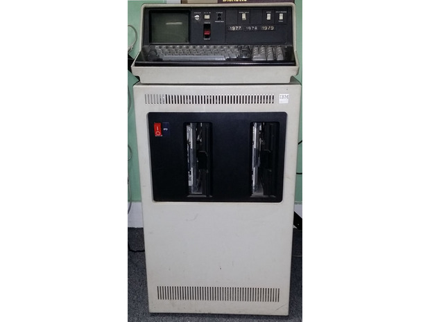 「IBM 5110」とフロッピーディスク装置

　1970年代の半ばにマイクロコンピュータを製造していた企業はAltairやAppleといった企業だけではない。Hewlett-Packard（HP）やIBMといった大企業も製造していた。しかし、それらは非常に高額な製品であり、法人向けに販売されていた。この写真の「IBM 5110」マイクロコンピュータは、キャビネットのような大きさの8インチのデュアルフロッピーディスク装置の上に乗せられているため、小さく見える。
