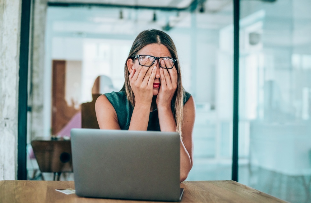 疲れ切った様子でノートPCの前に座る女性